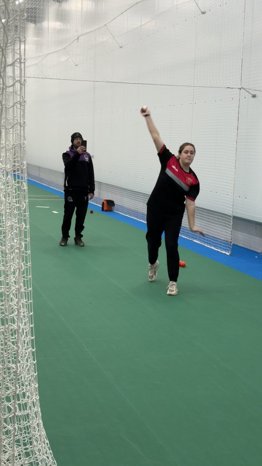 Centurion coach filming a young bowler on a phone during an indoor net session