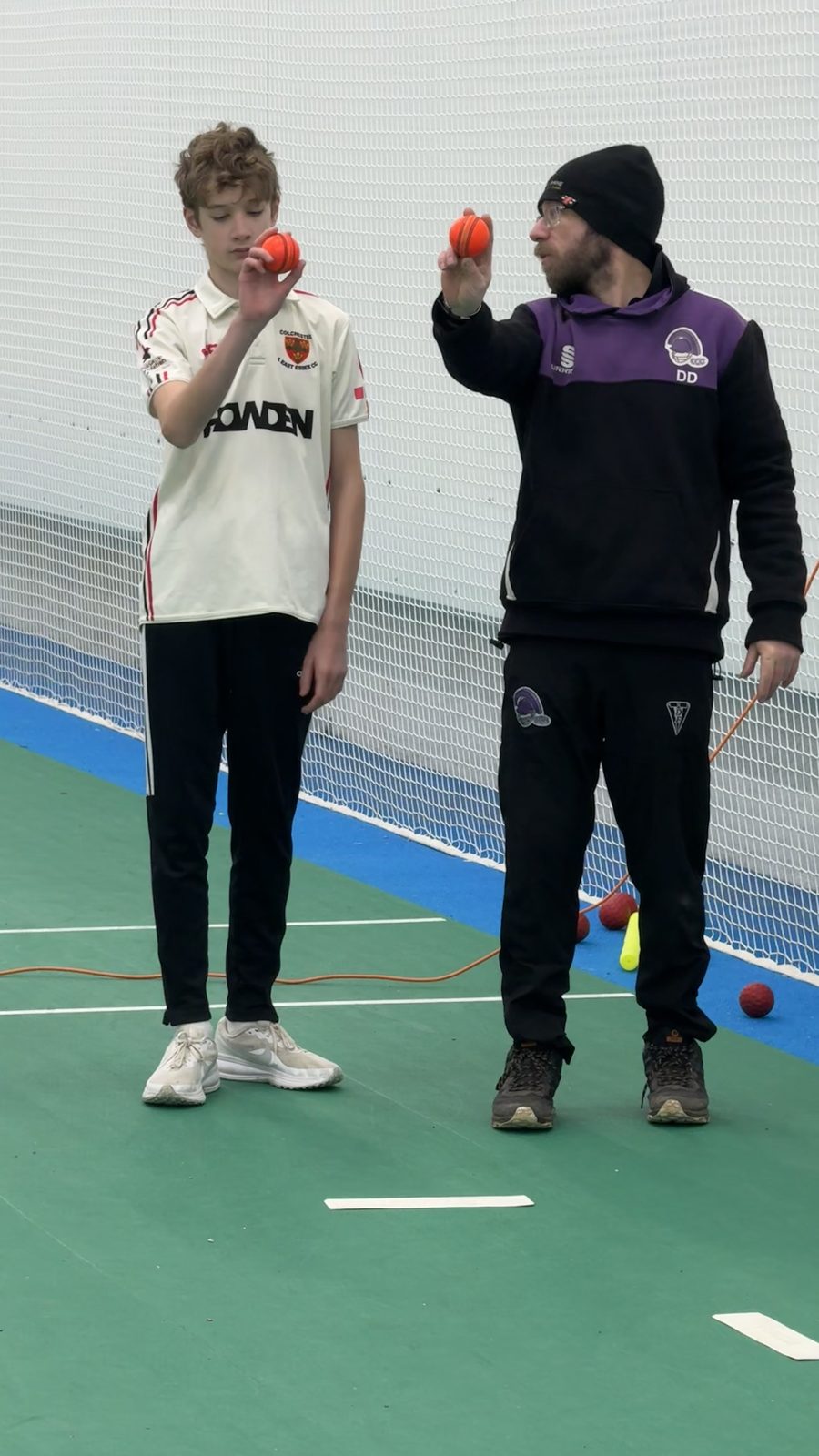 Coach and teenage bowler comparing ball grips side by side in an indoor lane